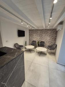 a waiting room with chairs and tables and a tv at La Maison de Rosaline Rooms in Barletta