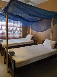 two beds in a room with a canopy bed at Flamingo Guest House ZNZ in Stone Town