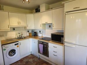 a kitchen with white cabinets and a washer and dryer at Gracian OMB Dublin Apartment in Dublin