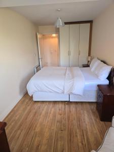 een slaapkamer met een groot wit bed en houten vloeren bij Gracian OMB Dublin Apartment in Dublin