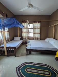 a bedroom with two beds and a ceiling fan at Flamingo Guest House ZNZ in Stone Town