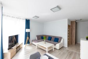 a living room with a couch and a table at Apartament 6M Rewal w cenie basen, jacuzzi, siłownia, sala zabaw, free private parking, Park Rozrywki HOSSOLAND 30 minut in Rewal +55 photos