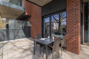 a patio with a table and chairs and a brick wall at Modern Studio with Terrace and Parking in Swinoujscie in Świnoujście