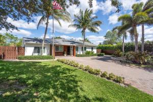 a house with palm trees in front of a driveway at Delray Oasis: Pool, Gazebo & Beach Access in Delray Beach