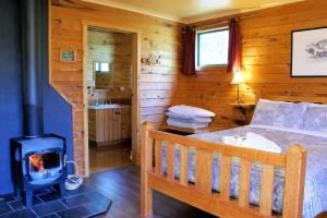 a bedroom with a bed and a wood stove at Cradle Highlander in Cradle Mountain