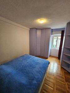 a bedroom with a blue bed and a window at Majka 2 Apartments in Kotor