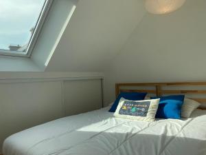 a bed with blue and white pillows and a window at 1009 - Maison du Val-André située à quelques pas de l'îlot du Verdelet et de la plage in Pléneuf-Val-André