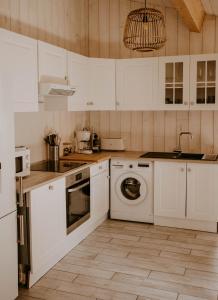 a kitchen with white cabinets and a washer and dryer at La cabane de Mamie classée 4 étoiles à 150m de la plage 2 chambres 3 lits in Biscarrosse