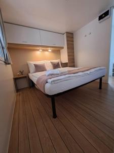 a large bed in a room with a wooden floor at Lucija Mobile Home in Biograd na Moru