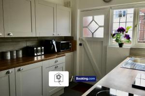 a kitchen with white cabinets and a sink and a window at Spacious Detached Highfield House By Your Stay Solutions Short Lets & Serviced Accommodation Netley Southampton Free Parking in Southampton