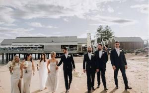 - un groupe de personnes en tenue de mariage marchant sur la plage dans l'établissement Beach shack!, à Sydney