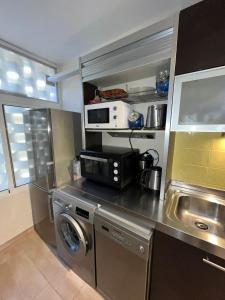 eine Küche mit einer Waschmaschine und einer Mikrowelle in der Unterkunft CERCA PLAYA - 6 PERSONAS - IDEAL FAMILIAS in Playa del Ingles