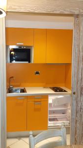 cocina naranja con fregadero y nevera en SUITE 225 Golf H PROMO SERVICE SRL en Castiglione della Pescaia