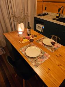 a wooden table with two plates and a bottle of wine at Chalé de Campo com hidro in Campo Alegre