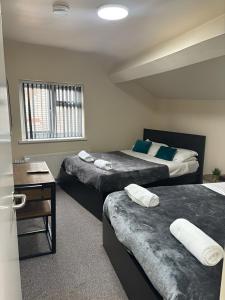 a room with three beds and a table and a desk at Tudors eSuites Budget Apartments in Birmingham