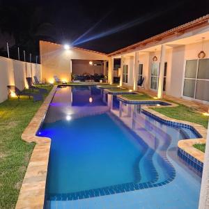 a swimming pool in a backyard at night at Chalés Mar e Sol in São Miguel do Gostoso