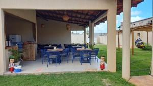 a patio with blue chairs and tables in a yard at Chalés Mar e Sol in São Miguel do Gostoso