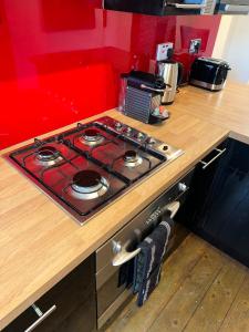 a stove top in a kitchen with a red wall at King’s Cross 2 bedroom apartment in London