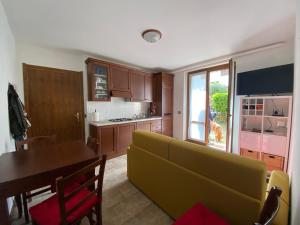 Una sala de estar con un sofá amarillo y una mesa. en Tiny House Valbondione [wi-fi], en Valbondione