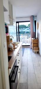 eine Küche mit weißen Schränken und Blick auf einen Balkon in der Unterkunft Terrasses 2 - Plage et commerces à 400 m in Le Grau-du-Roi + 15 Fotos