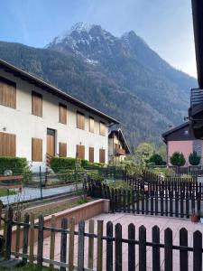 un edificio con una valla frente a una montaña en Tiny House Valbondione [wi-fi], en Valbondione