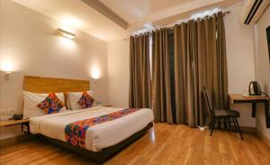 a hotel room with a bed and a desk and a chair at Hotel Majestic JPM - East Of Kailash in New Delhi