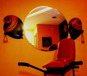 Loft Motel في سانتوس: غرفة بها كرسي احمر ومرآة