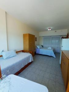 a hotel room with two beds and a refrigerator at Abanico in Puerto Madryn