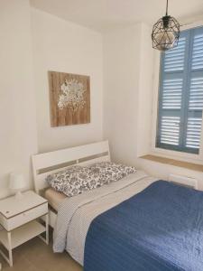 ein weißes Schlafzimmer mit einem Bett und einer blauen Decke in der Unterkunft Chic And Modern Apt 5 Min From The Beach in Marseille