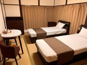 Habitación de hotel con 2 camas, mesa y silla en 東京近隣 蔵元荘 駅近 交通便利, en Matsudo