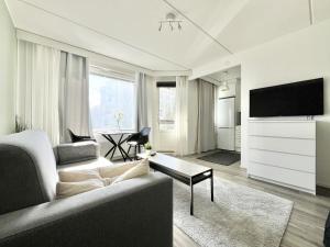 ein Wohnzimmer mit einem Sofa und einem TV in der Unterkunft Tammer Huoneistot - City Suite 1 - Sauna, Balcony & Free parking in Tampere