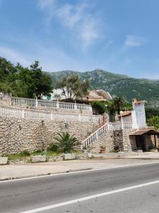 a stone wall with a white fence and a road at Samo Skreneš in Brežani