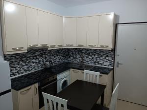 a kitchen with white cabinets and a table and a dishwasher at Diamond Apartment Vlore in Vlorë