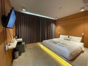 a bedroom with a bed and a flat screen tv at The Palette Bangkok Hotel in Bangkok