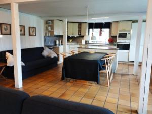 a living room with a black table and a kitchen at (id075) Ø. Tovrupvej 1 in Esbjerg