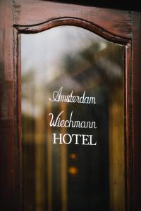 a sign that says australian welcome hotel in a mirror at Amsterdam Wiechmann Hotel in Amsterdam