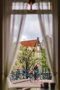 eine Person, die ein Fahrrad durch ein Fenster fährt in der Unterkunft Amsterdam Wiechmann Hotel in Amsterdam