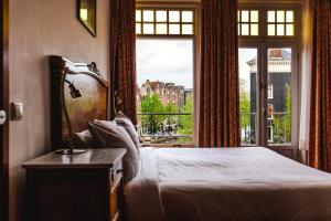 a bedroom with a bed and a large window at Amsterdam Wiechmann Hotel in Amsterdam
