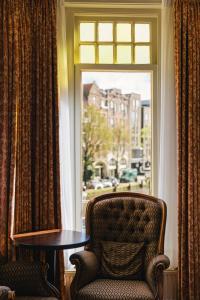 a chair and a table in front of a window at Amsterdam Wiechmann Hotel in Amsterdam