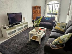 ein Wohnzimmer mit einem Sofa und einem TV in der Unterkunft Villa Crisantemos in Nerja