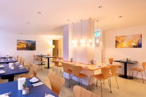 a dining room with tables and chairs and paintings at Select Hotel Silence Garden Köln in Cologne