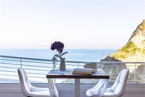 APARTAMENTOS KRESALA - Vistas al mar في جيتاريا: طاولة مع كرسيين و مزهرية مع الزهور على شرفة