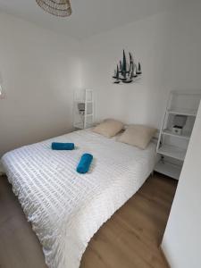 Una cama blanca con zapatillas azules encima. en La Bernique blanche de Perros vue mer 4 personnes, en Perros-Guirec