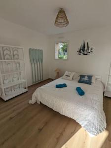 Un dormitorio con una gran cama blanca con almohadas azules. en La Bernique blanche de Perros vue mer 4 personnes, en Perros-Guirec