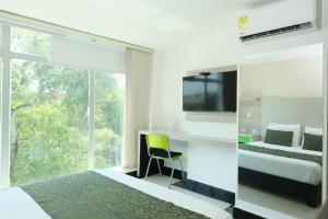 a bedroom with two beds and a desk and a window at Hotel Genova Prado in Barranquilla