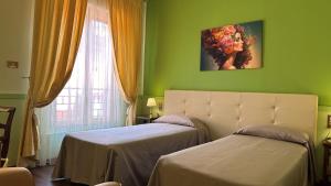 a green room with two beds and a window at Hotel Roma in Bologna