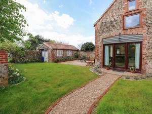 a brick house with a garden and a patio at The Little Hay Barn in Norwich