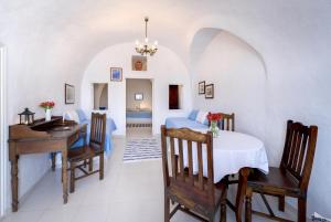 a dining room with a table and a desk at Chelidonia Traditional Villas in Oia