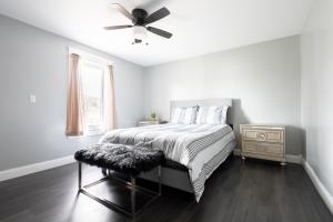 a white bedroom with a bed and a ceiling fan at The Texas Hold-em Duplex- 3BR Free Parking, Minutes From Falls & Casino in Niagara Falls