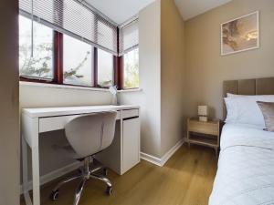 Schlafzimmer mit einem Schreibtisch und einem Bett mit Fenstern in der Unterkunft Cosy Modern Apartment Colchester in Colchester